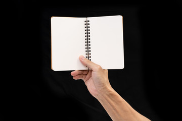 Obraz premium Man hand holding blank notebook on black background