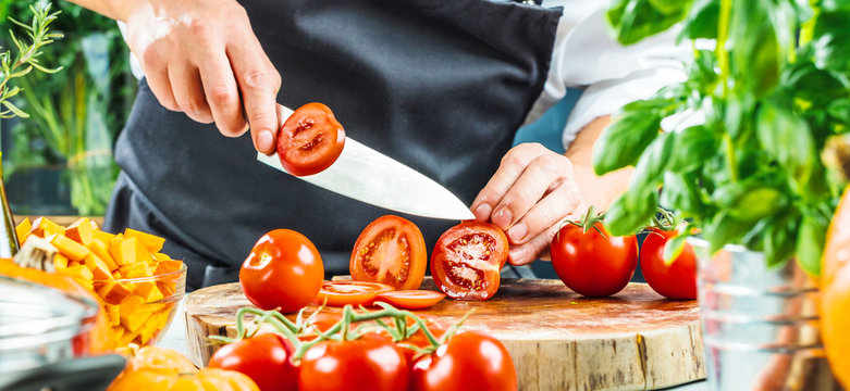 Koch schneidet frische rote Tomaten in Restaurant k&uuml;che 
