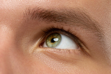 Fototapeta na wymiar Caucasian young man's close up portrait. Beautiful male model with well-kept skin. Concept of human emotions, facial expression, sales, ad, beauty, hope. Green eye looking up and eyebrow.