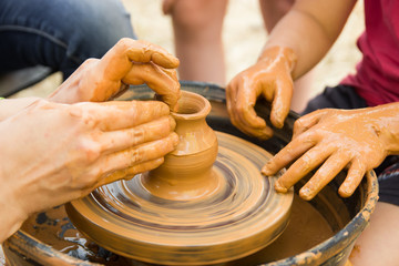 A close up view on ceramic production process on potter's wheel with children. Clay crafts with kids concept.