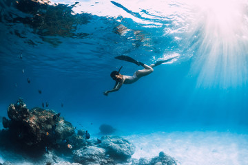 Woman freediver with fins underwater. Freediving and beautiful light in ocean