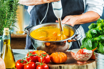 Chefkoch mit stabmixer kocht leckere kürbissuppe