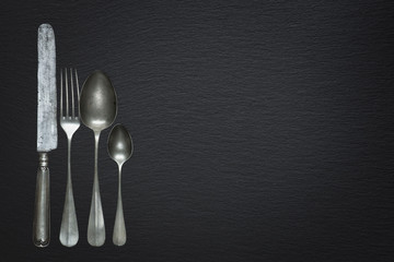 Vintage cutlery on a black slate