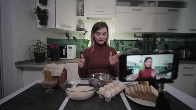 fashion blogger, ute housewife recording recipes for her vlog on a social network on her phone and showing products to the camera