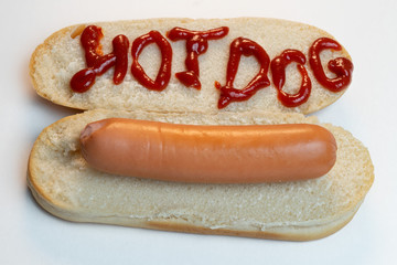 Hot dog bun or bread with boiled sausage on white isolated background. The inscription ketchup Hot-dog . Top view. Close-up