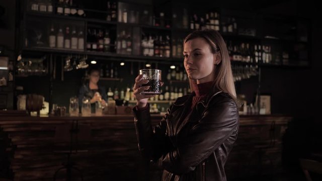 fashionable cafe, a beautiful girl in a great bar with a tasty drink in her hands looks at the bartender's work, then drinks a prepared cocktail and looks at the camera and smiles