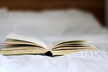 Open book on a bed. Selective focus.