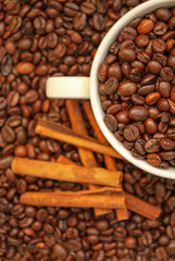 cup with coffee beans and cinnamon sticks