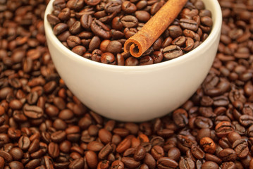 cup with coffee beans and cinnamon sticks
