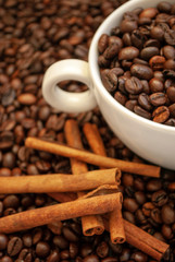 cup with coffee beans and cinnamon sticks