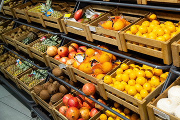 Diagonal view of wooden lug boxes with exotic fruit on counter in supermarket