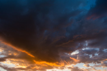 Storm clouds at sunset in orange and blue colors