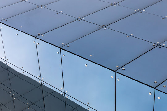 Modern building facade with glass surface, diagonal view close-up.