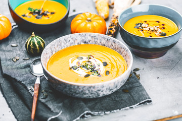 close-up view of pumpkin soup puree in bowls, corn and pumpkins on table
