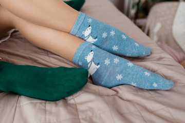Soft photo of woman and man on the bed. Female and male legs of couple in warm socks. Christmas, love, lifestyle concept