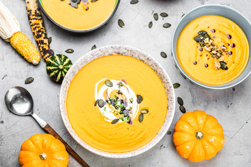 close-up view of pumpkin soup puree in bowls, corn and pumpkins on table