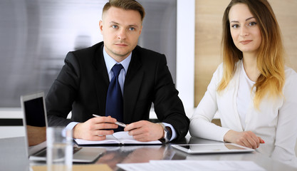 Business people or lawyers discussing questions at meeting in modern office. Unknown businessman and woman with colleague sitting and working at the glass desk. Teamwork and partnership concept