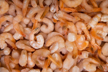 Pile of uncooked, lightly frozen shrimps and prawns. Orange seafood texture, background, top view.