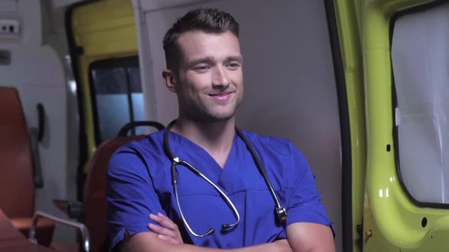 Pleased corpsman stand on the background of ambulance car.