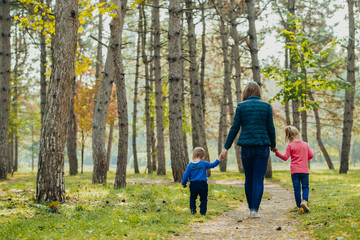 Obraz premium Mom with daughter and son are walking in the autumn park. Family for a walk in the forest