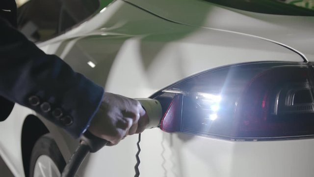 Hand of man that connects plug for charging to electric car