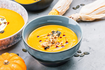close-up view of pumpkin soup puree in bowls, corn and pumpkins on table