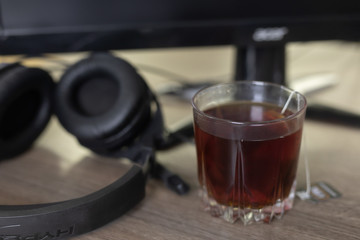 on the desktop a glass of tea, left headphones near the computer. Work lifestyle concept. office workplace