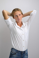 portrait of a young beautiful girl in a white shirt and jeans on a gray background
