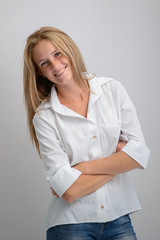 portrait of a young beautiful girl in a white shirt and jeans on a gray background