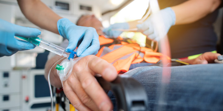 Not&auml;rztin bringt Injektionsnadel and Hand im Krankenwagen an