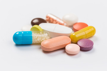 Assorted pharmaceutical medicine pills, tablets and capsules.Heap of assorted various medicine tablets and pills different colors on white background. Top view.Copy space