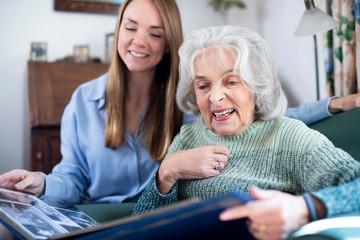 Grandmother Looking At Photo Album With Adult Granddaughter