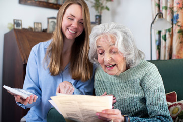 Woman Helping Senior Neighbor With Bills And Paperwork