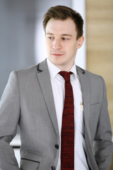 Businessman headshot while he standing straight in modern office. Success and business workplace concept