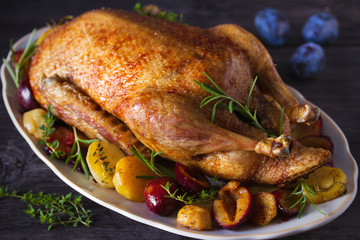 Baked duck with potatoes, plums, rosemary and thyme, close-up on plate. Horizontal