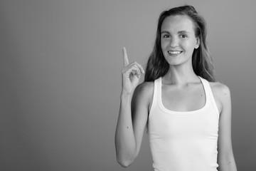 Young beautiful woman smiling and pointing finger up