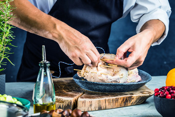 partial view of male chef in apron preparing stuffed duck