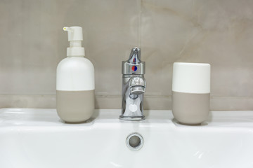 Fototapeta na wymiar Soap and shampoo dispensers near Ceramic Water tap sink with faucet in expensive loft bathroom