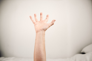 Hand vor weißer Wand vor Bett in Positionierung