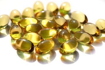 Capsules with fish oil, vitamins A and D. Closeup of a pile of gold vitamins, gold liver oill.