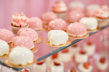 Wedding candy bar with pink and white deserts. Strawberry cupcakes, jelly and modern desserts.