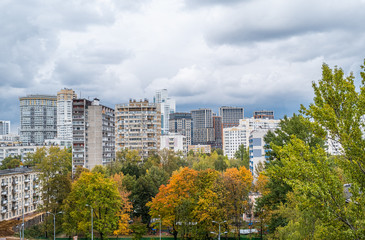 View to the residential buildings from the hill, overgrown with grass and wild flowers of goldenrod. Concept of ecology in a city, suburb area, eco-friendly district