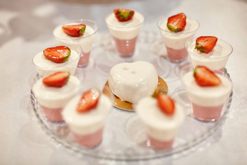 Wedding candy bar with pink and white deserts. Strawberry cupcakes, jelly and modern desserts.