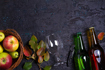 Bottles and glass of apple and pear cider with fruits on black background. View from above, top view. Room for text, copy space