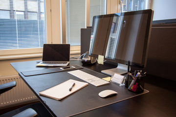 Office desk with paper and pen. Laptop with external screen.