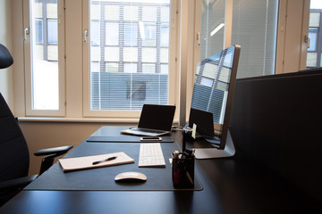 Office desk with paper and pen from the side. Laptop with external screen.