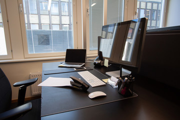 Office desk with paper and stapler. Laptop with external screen.