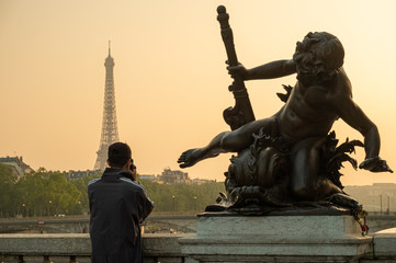 Fototapeta na wymiar Statue of Nymphs with locks on Alexandre III bridge with Eiffel Tower in the background at sunset time in Paris