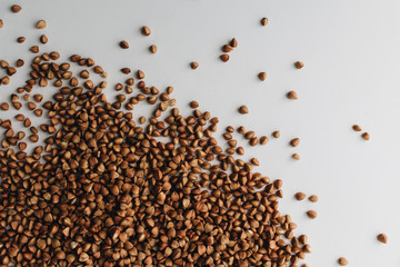 Scatterd raw buckwheat on white background 
