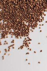 Scatterd raw buckwheat on white background 